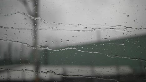 Water-drops-moving-from-left-to-right-on-train-window-glass,-city-background