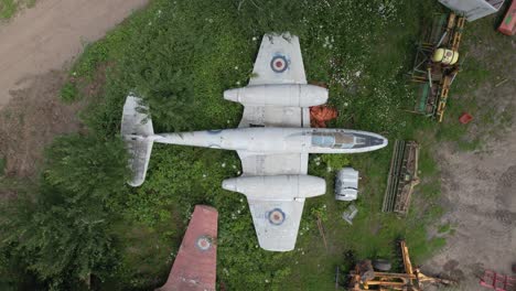 Aerial-shot-of-the-Gloster-Meteor-vintage-military-RAF-airplane-jet-parked-in-the-greenery-in-an-English-village---top-down-cinematic-shot