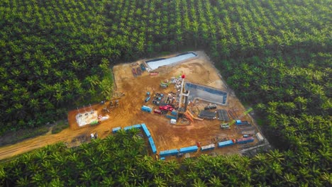 Cinematic-4K-Drone-Footage-of-Onshore-Drilling-Rig-equipment-structure-for-oil-exploration-and-exploitation-in-the-middle-of-jungle-surrounded-by-palm-oil-trees-during-sunset-and-high-oil-price