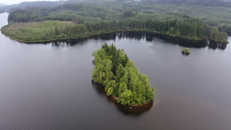 Luftaufnahme-Einer-Kleinen,-Mit-Bäumen-Bedeckten-Insel-Inmitten-Eines-Schottischen-Sees-An-Einem-Bewölkten-Tag