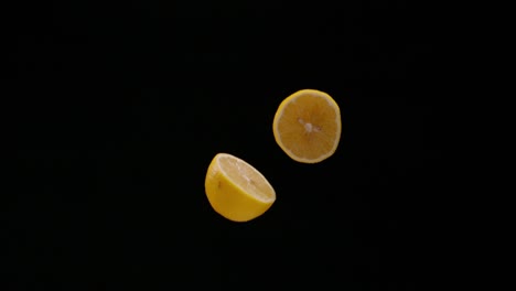 Halbierte-Zitrone,-Die-Isoliert-Auf-Schwarzem-Hintergrund-Herunterfällt,-Zeitlupe