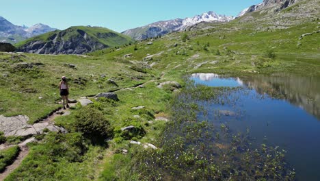 Woman-Hikes-Wetlands-Trail-along-Mountain-Lake-in-French-Alps---Aerial-Follow