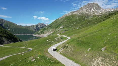 RV-Motorhome-drives-along-Mountain-Lake-Lac-de-Grand-Maison-in-French-Alps---Aerial-Follow