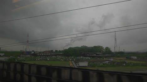 View-of-industrial-area-through-train-window-on-cloudy-day,-slow-motion,-Japan