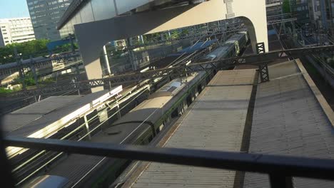 JR-train-passing-between-two-railway-platforms,-view-from-above,-Japan