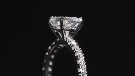 Close-up,-diamond-engagement-ring-rotating-against-black-studio-background