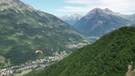 Paraglider-floating-above-Eau-d'Olle-valley-in-Alpe-d'-Huez,-French-Alps---Pan-Left