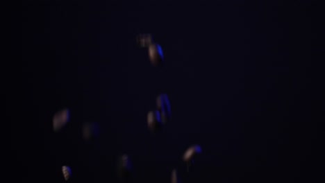 Slow-motion-shot-of-coffee-beans-falling-through-a-dark-space