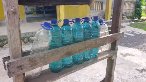 Row-of-plastic-water-bottles-filled-with-blue-petrol-fuel-gasoline-at-roadside-stall-on-Timor-Leste-and-Indonesia-border,-Southeast-Asia