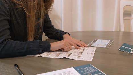 Woman-with-long-hair-reading-through-her-mail-in-ballot's-political-candidate-options