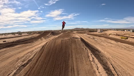 Motorcycles-racing-on-an-off-road-track-with-high-jumps-and-stunts---first-person-view-drone