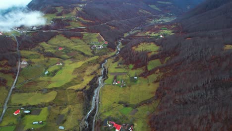 Bunte-Landschaft-In-Den-Albanischen-Alpen,-Häusern-Und-Wiesen,-Umgeben-Von-Herbstfarben-Der-Berge