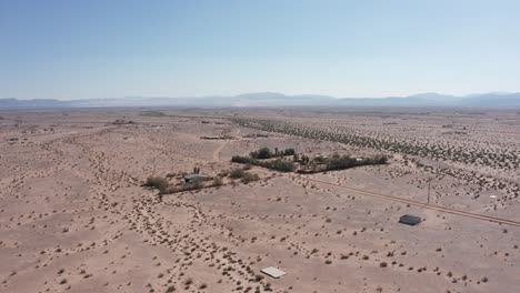 Aufsteigende-Und-Schwenkende-Luftaufnahme-Von-Verstreuten-Wüstenhäusern-In-Der-Kargen-Mojave-Wüste-Von-Kalifornien