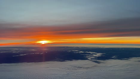 Aerial-view-of-a-dawn-over-Germany-flying-southward-near-Frankfurt-in-a-cold-winter-day-with-an-intense-orange-sky-over-foggy-valleys