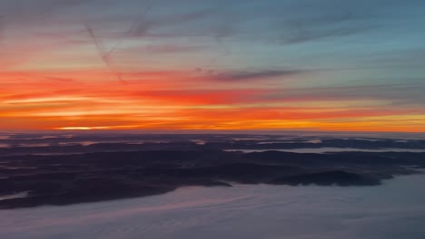 Unique-aerial-view-from-a-jet-cockpit-flying-over-Germany-at-dawn-with-a-colorful-orange-sky