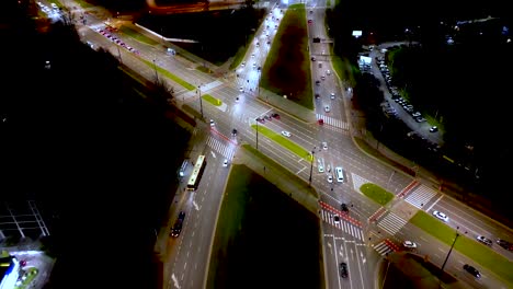 Low-flying-aerial-tilting-shot-of-multi-lane-road-in-modern-city-center-with-skyscrapers-at-night