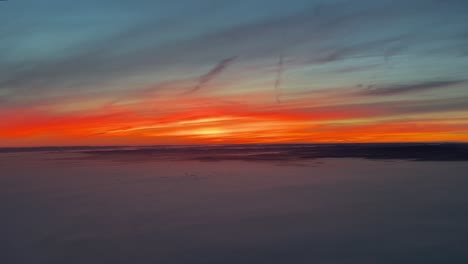 Sunrise-over-Germany-near-Frankfurt-from-a-jet-cockpit-after-depature-with-an-intense-red-sky-in-a-cold-winter-moorning
