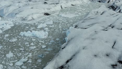 Bergy-bits-float-in-glacial-lake-of-Vatnajokull-glacier,-Iceland---aerial