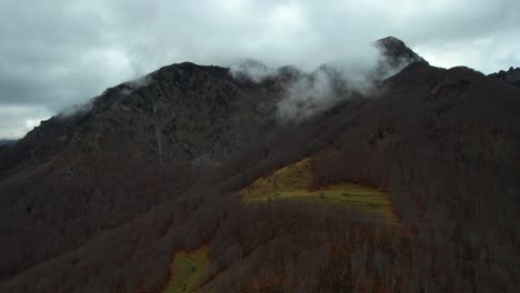 Forest-hill-with-leafless-trees-in-Autumn-and-mountains-steaming-on-a-rainy-day-in-Albanian-Alps