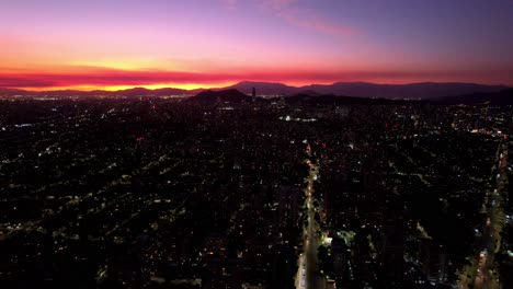 Aerial-Drone-Fly-Above-Santiago-de-Chile-City-Evening-Traffic-Pink-Yellow-Sunset-near-Athens-Roundabout,-Modern-Latin-American-Downtown