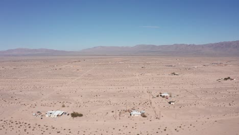 High-and-wide-aerial-shot-of-scattered-homes-in-a-barren-and-sparse-Californian-desert