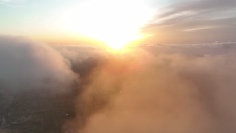 Aerial-of-drone-flying-through-the-clouds-revealing-the-sun-during-sunrise-on-mallorca