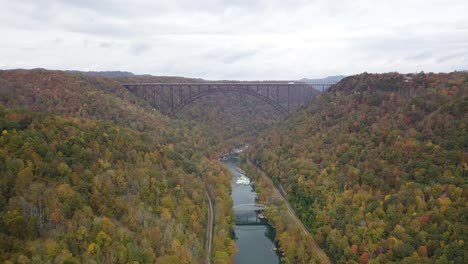 Slow-aerial-dolly-of-cars-driving-along-the-River-Gorge-Bridge-with-autumnal-trees