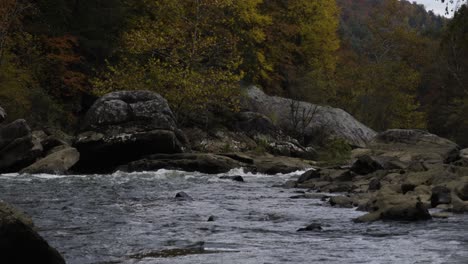 Statische-Aufnahme-Eines-Schnell-Fließenden-Abschnitts-Der-Flussschlucht-Mit-Herbstlichen-Bäumen-Dahinter