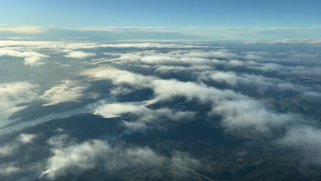 Aerial-view-from-a-jet-cockpit-after-sunrise-flying-southward-over-Germany-near-Frankfurt-with-the-view-of-fog-in-the-valleys-and-some-few-clouds