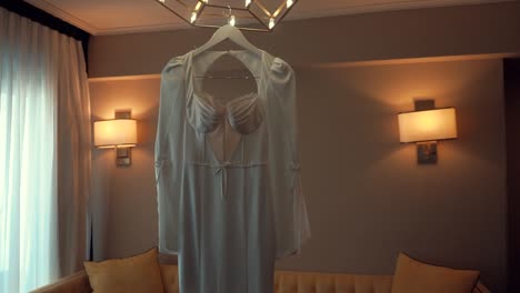 A-smooth-shot-of-a-bridal-wedding-dress,-hanging-in-a-decorate-room
