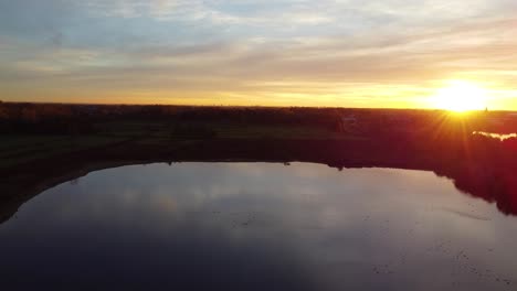 Wolkengebilde-Reflektiert-Auf-Klarem-Seewasser-Während-Des-Goldenen-Sonnenuntergangs,-Luftdrohnenansicht