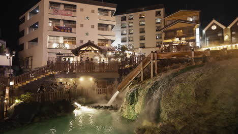 Part-of-Kusatsu-Onsen’s-symbolic-hot-water-field-at-night-time-with-steaming-water-coming-out-and-tourists-taking-pictures