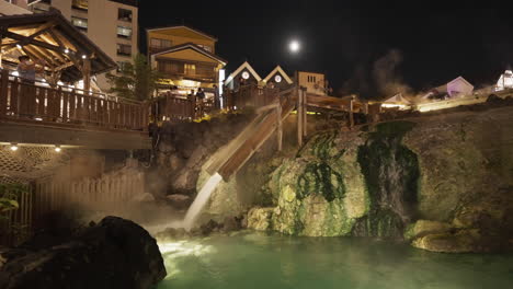 Famous-Yubatake-in-Kusatsu,-Japan-during-evening-light-up-with-tourists-in-traditional-Japanese-summer-kimono-taking-photographs-of-the-beautiful-hot-spring-waterfall