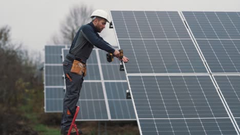 A-professional-man-in-a-special-uniform-installs-a-solar-panel-at-a-solar-power-plant