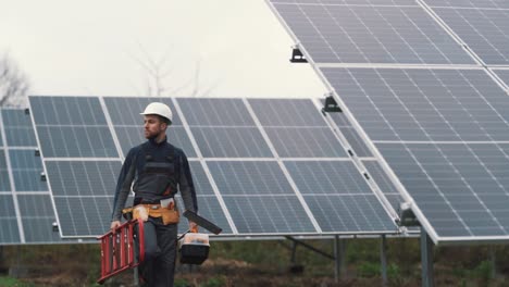 A-young-technician-in-work-uniform-inspects-the-solar-power-plant-while-walking-with-the-necessary-equipment