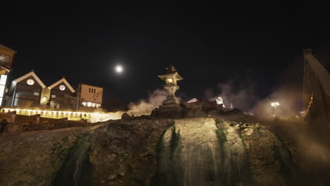 Aufnahme-Einer-Japanischen-Steinlaterne-Auf-Einem-Dampfenden-Wasserfall-Einer-Heißen-Quelle-Im-Dorf-Kusatsu-Onsen-Am-Abend-Nach-Dem-Aufleuchten