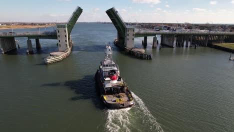An-aerial-view-behind-a-tugboat-heading-inland-from-the-sea