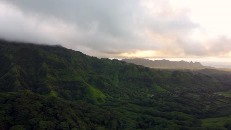Cinematic-nature-aerial-view-of-green-mountains-under-tropical-rain-clouds-at-beautiful-sunrise-on-Kauai-island,-Hawaii-Dramatic-nature-aerial-view-of-Rainforest-Tropical-jungle-of-Kauai