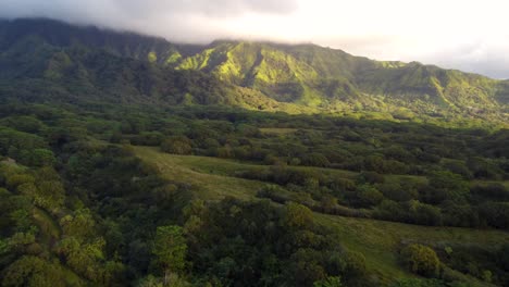 Cinematic-forest-flyover-at-beautiful-sunrise-on-Kauai-Hawaii-island-revealing-green-mountains-under-tropical-rain-clouds