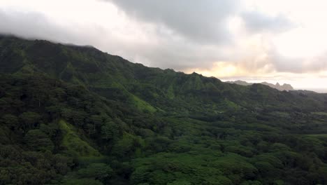 Cinematic-nature-aerial-view-of-green-mountains-under-tropical-rain-clouds-at-beautiful-sunrise-on-Kauai-island-in-Hawaii-Dramatic-nature-aerial-view-of-Rainforest-Tropical-jungle-of-Kauai