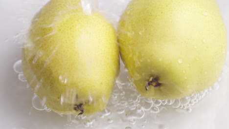 Yellow-pear-on-a-blue-dark-background-with-drops-of-water-rolling-down-the-pear-and-flowing-splashing-with-isolated-background