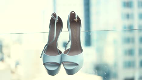 A-hanging-white-pair-of-wedding-hill-shoes,-close-up-shot,-slow-motion
