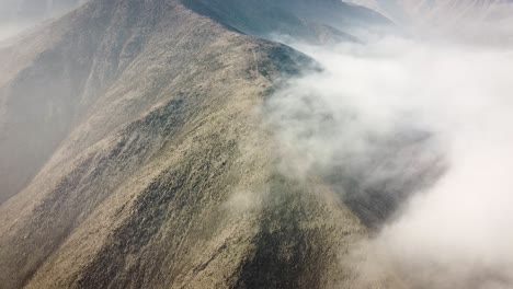 Drohnenaufnahme-Eines-Bergkamms-Mit-Einer-Nebligen-Wolke-Bei-Sonnenaufgang-In-Der-Stadt-Lima