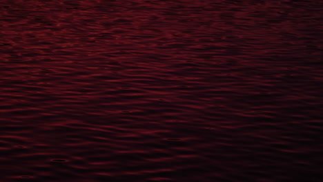 Red-color-sunset-reflecting-on-ocean-water-surface,-ripples