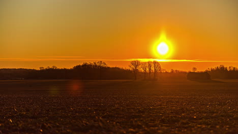 The-golden-sunrise-breaks-over-the-horizon-and-morning-mist-to-illuminate-the-farmland-fields---time-lapse