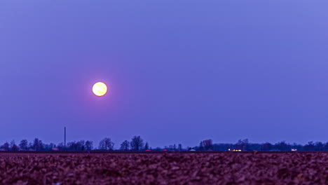 Full-moon-setting-down-behind-agriculture-field,-fusion-time-lapse