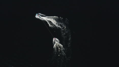 Aerial-view-of-a-ringo-ride-behind-a-jetski-in-deep-dark-water-in-a-river-in-Sweden