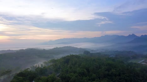 Drone-shot-of-forest-and-hill-in-the-misty-morning-with-sunrise-sky-on-the-background