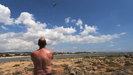 Back-view-of-man-holding-toy-kite-on-beach-on-summer-sunny-day