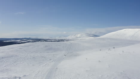 Amplia-Vista-Aérea-De-Turistas-Montando-Motos-De-Nieve-A-Través-De-La-Nieve-En-El-Norte-De-Suecia-Durante-El-Invierno